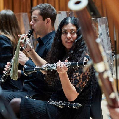 Students on stage holding wind instruments as part of the orchestra